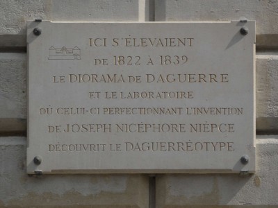 Plaque fixed high on wall of the north end (at rue Léon Jouhaux) of Caserne Verines (which fronts along Place de la Republic) commemorating the site of Daguerre's Diorama